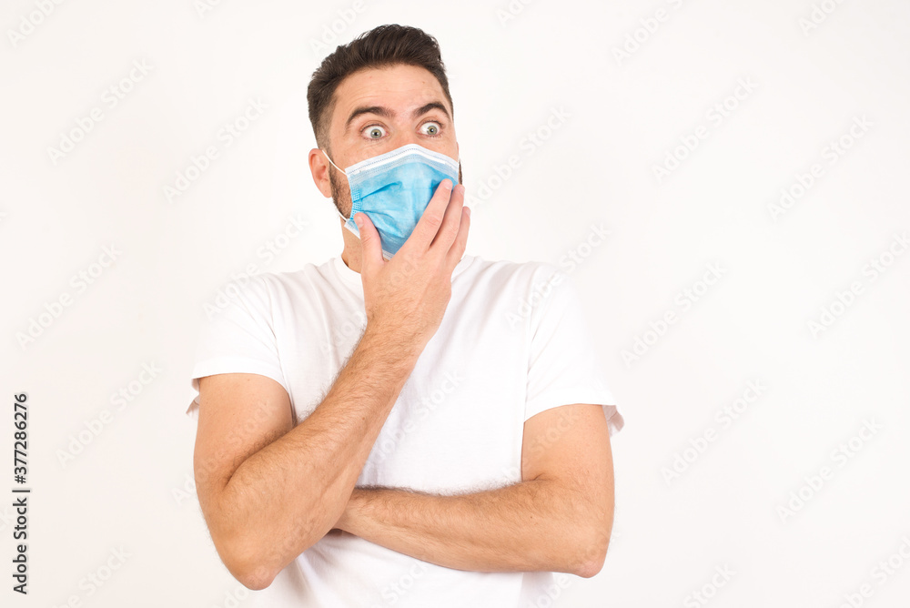 Anxiety - a conceptual image of a handsome caucasian male covering his mouth with his hands and standing indoors. Scared from something or someone bitting nails Anxiety - a conceptual image of a handsome caucasian male covering his mouth with his hands and standing indoors. Scared from something or someone bitting nails
