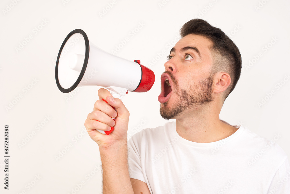 Handsome Caucasian man shouting with megaphone, isolated over white background. Front view portrait. Handsome Caucasian man shouting with megaphone, isolated over white background. Front view portrait.