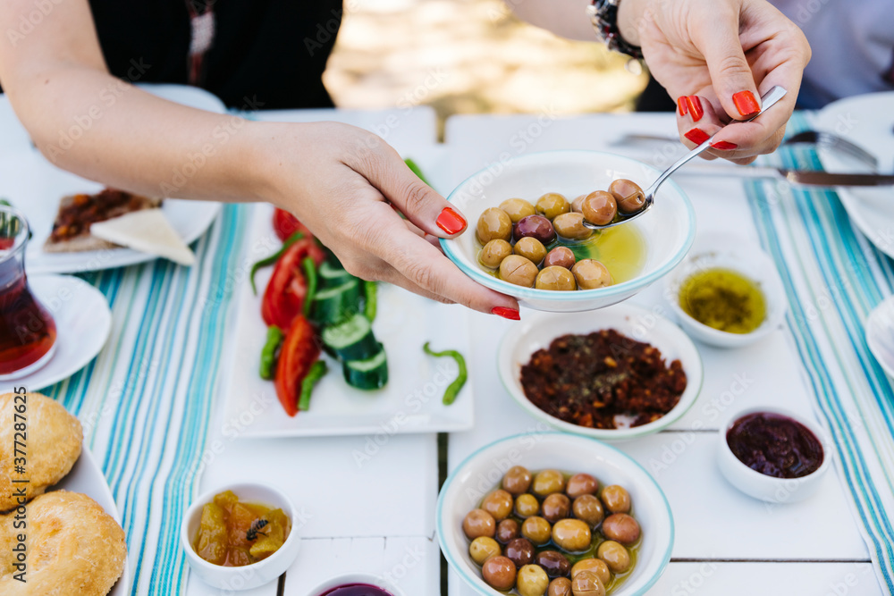 a woman is holding green olive at Turkish Breakfast table a woman is holding green olive at Turkish Breakfast table