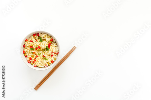 Instant noodle with pepper,peas, chopstick and greens. White background top view copy space
