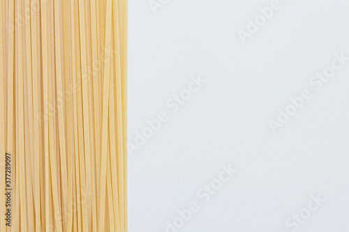 Photos Bunch of raw linguine pasta on left side of white background, copy space