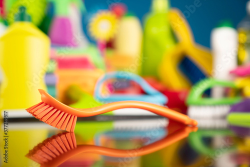 House and office cleaning theme. Colorful cleaning kit on shing brown table and blue background.