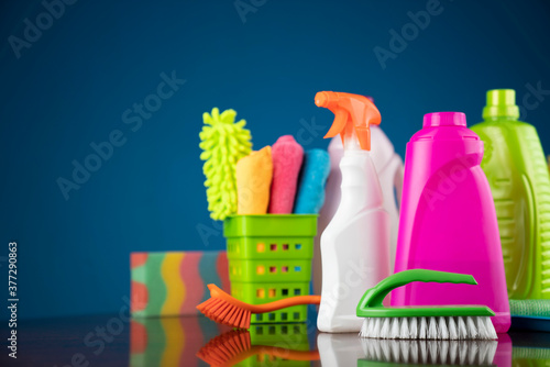 House and office cleaning theme. Colorful cleaning kit on shing brown table and blue background.