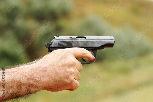     A gun in a male hairy hand ready for a shot. photo