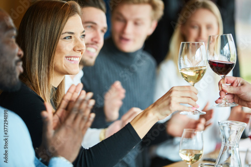 Junge Frau beim Anstoßen mit einem Glas Wein