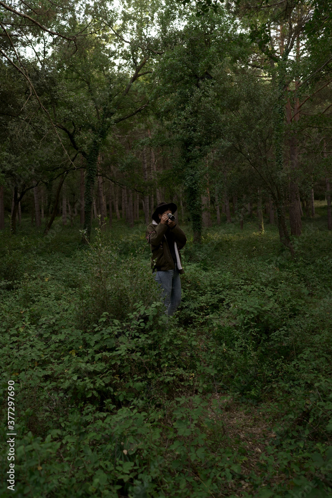 Isolated young girl wearing a hat, about to take a landscape photo with a camera