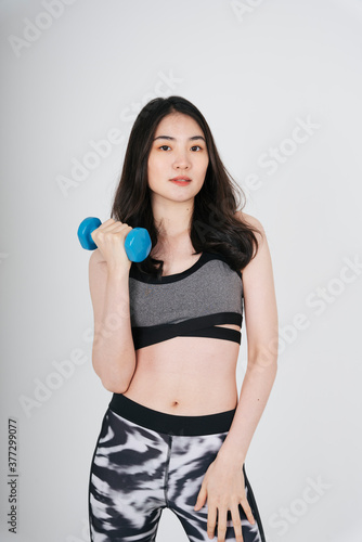 Beautiful slim asian woman work out with dumbbell over white background.