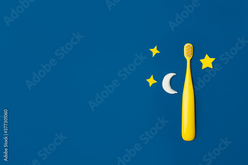 Yellow Cute kids toothbrush, moon, stars on classic blue background. Funny teaching children to easy brush teeth. Social media banner, daily routine - evening tooth hygiene. Dental healthcare concept photo