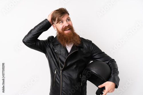 Redhead man with long beard holding a motorcycle helmet over isolated white background laughing