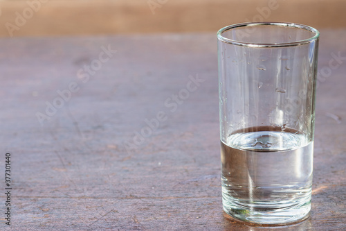 A glass of fresh drinking water on a wooden table.