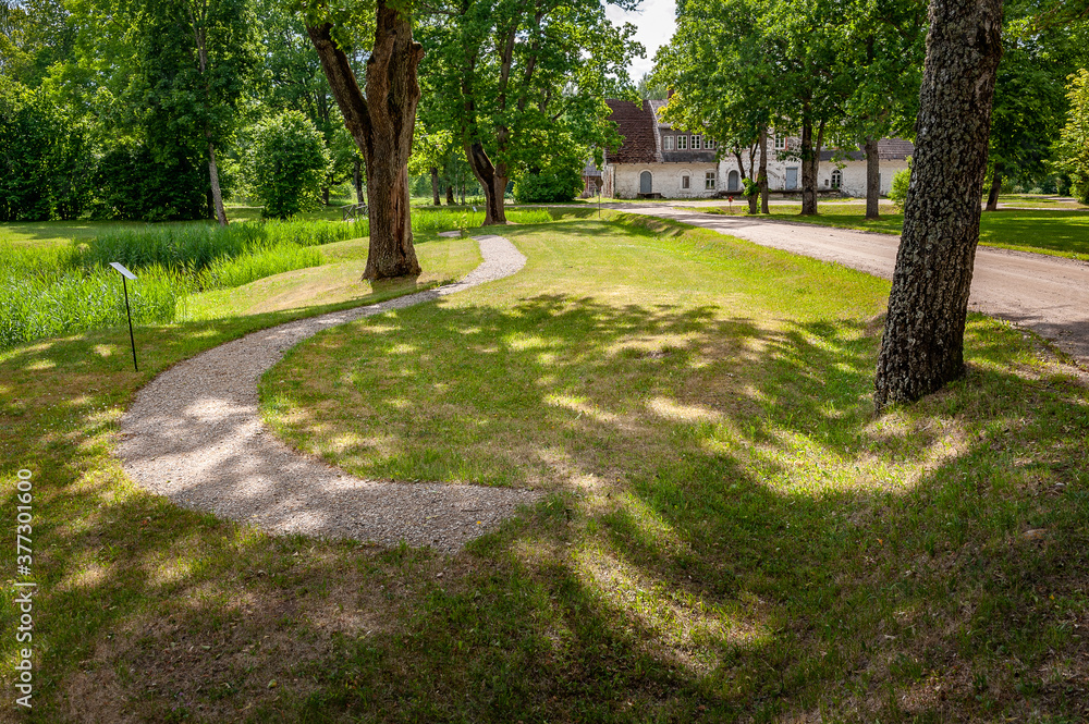 Footpath winding through summer park and old dairy plant in the background.