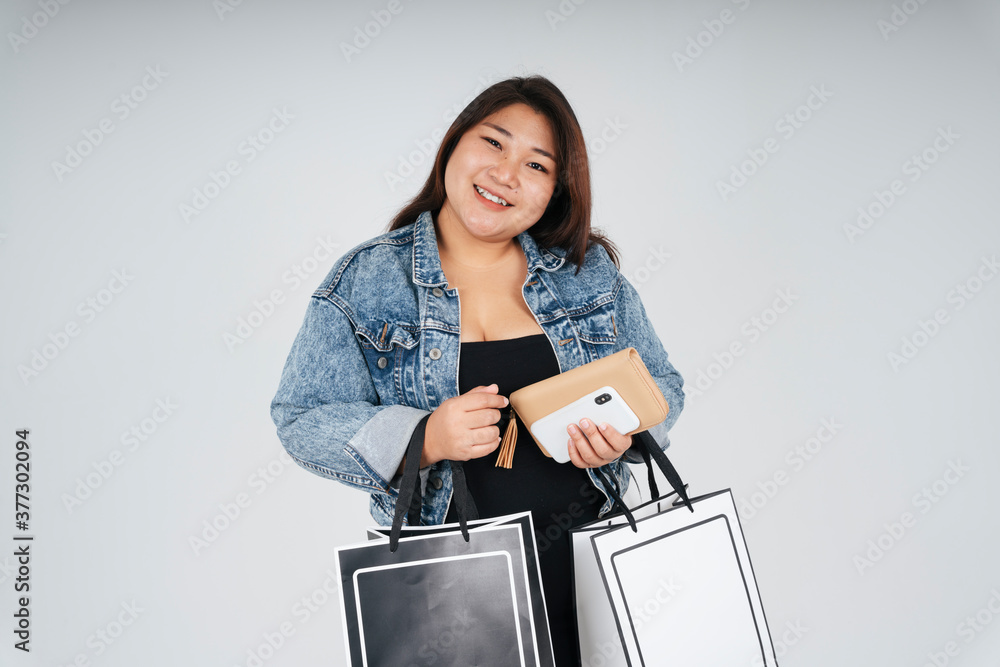 Chubby woman in black dress and jeans jacket holding shopping paper bags isolate over white background. Chubby woman in black dress and jeans jacket holding shopping paper bags isolate over white background.
