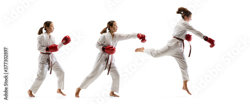 High jump. Junior in kimono practicing taekwondo combat  martial arts. Young female fighter with red gloves training on white studio background in motion  dymanic. Concept of healthy lifestyle  action