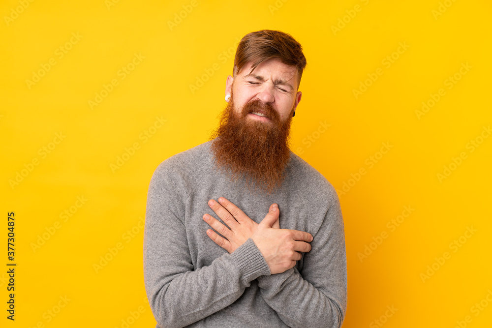 Redhead man with long beard over isolated yellow background having a pain in the heart Redhead man with long beard over isolated yellow background having a pain in the heart