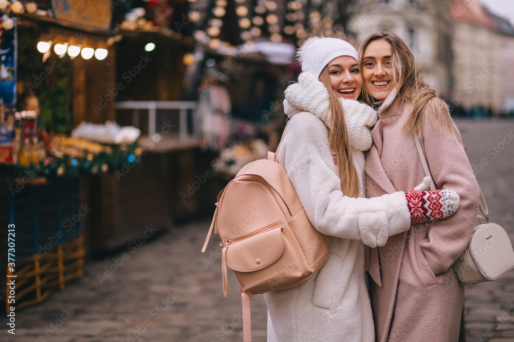 Obraz premium two girls stand at the christmas market decorated with christmas