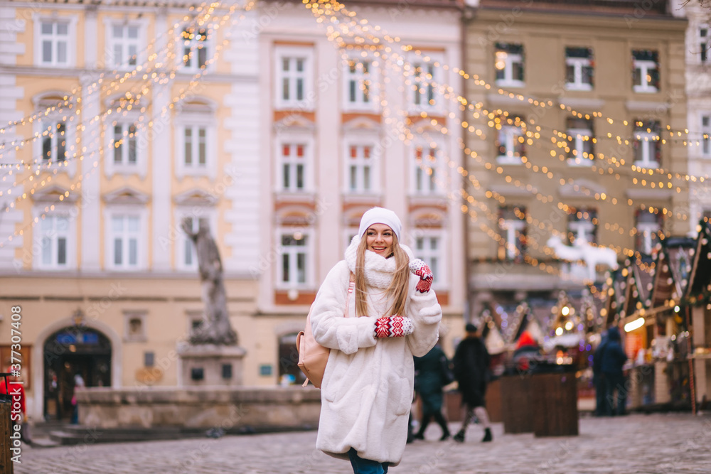 A girl on background of a winter city. Beautiful young happy girl on the streets of a snowy city. She enjoys Christmas mood in city.