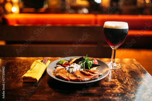 Meat and vegetables dish with a glass of dark beer