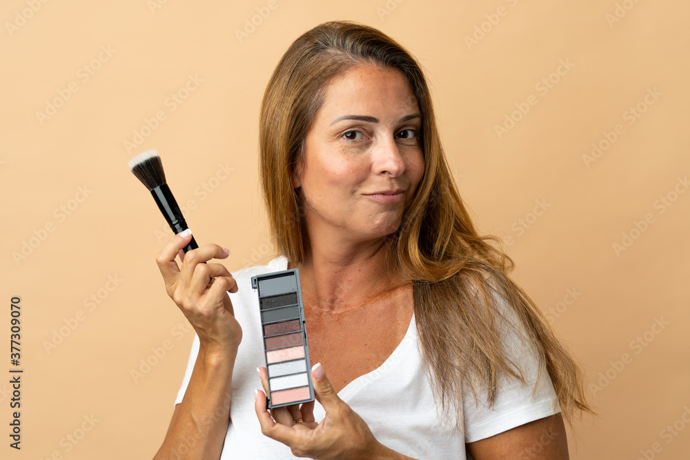 Middle age brazilian woman isolated on beige background with makeup palette Middle age brazilian woman isolated on beige background with makeup palette