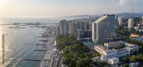 Blue black sea coast in Sochi with houses under the summer sky. Beach. Modern houses and hotels by the sea.