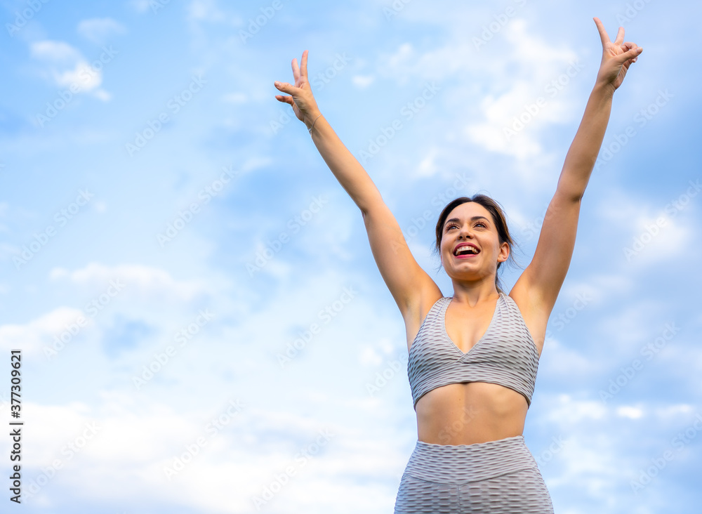 Fitness session with a young Caucasian blonde, very cheerful doing exercises, with the sky in the background, symbol of vistoria, gray sport suit, fit girl, healthy life, exercise in the field Fitness session with a young Caucasian blonde, very cheerful doing exercises, with the sky in the background, symbol of vistoria, gray sport suit, fit girl, healthy life, exercise in the field