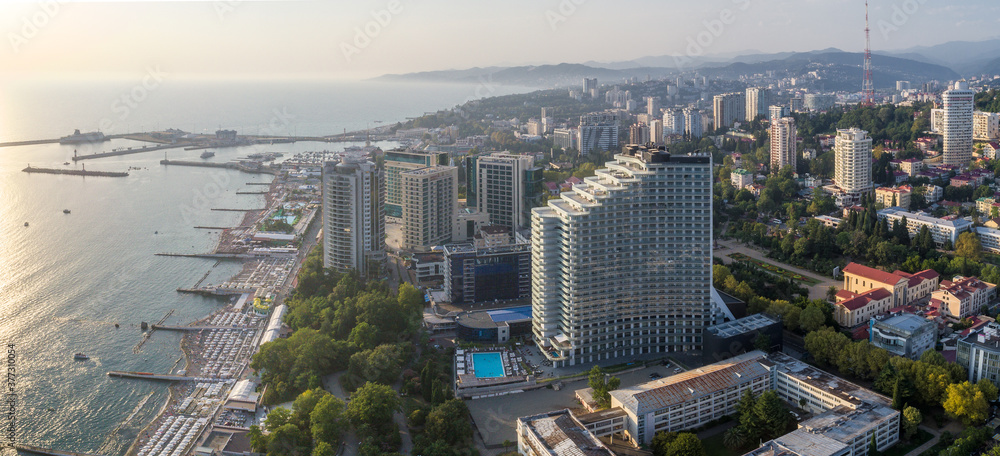 Blue black sea coast in Sochi with houses under the summer sky. Beach. Modern houses and hotels by the sea.