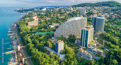 Blue black sea coast in Sochi with houses under the summer sky. Beach. Modern houses and hotels by the sea.