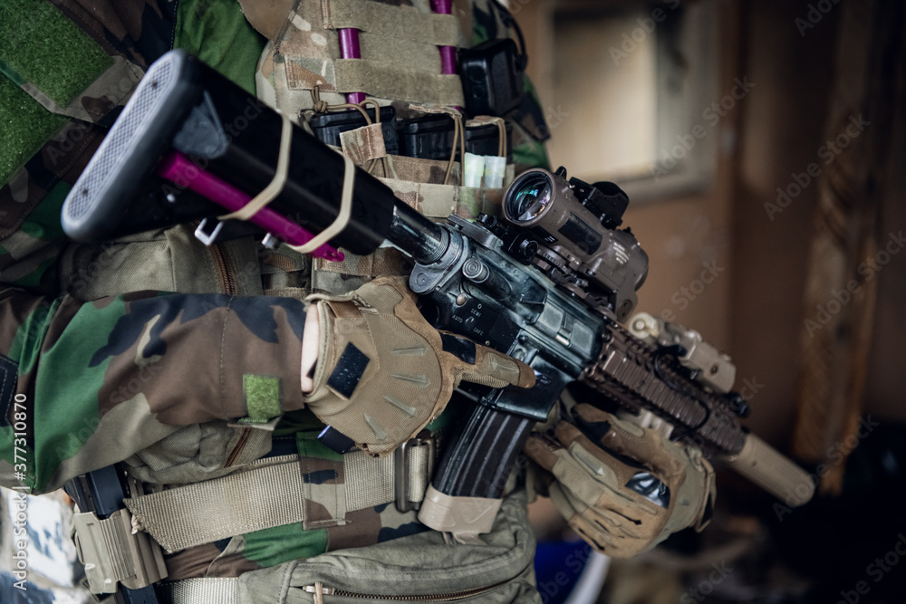 Weapons close-up on a military man standing inside the building and waiting for command. Weapons close-up on a military man standing inside the building and waiting for command.