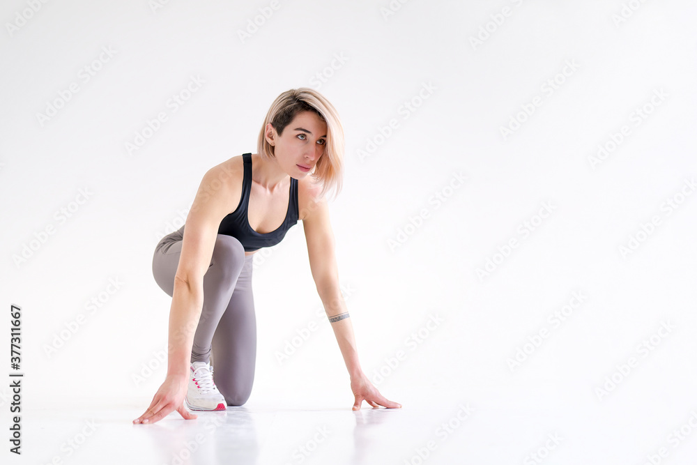 Healthy young woman preparing for a run. Fit female athlete ready for a spring over white background with copy space. Isolate Healthy young woman preparing for a run. Fit female athlete ready for a spring over white background with copy space. Isolate