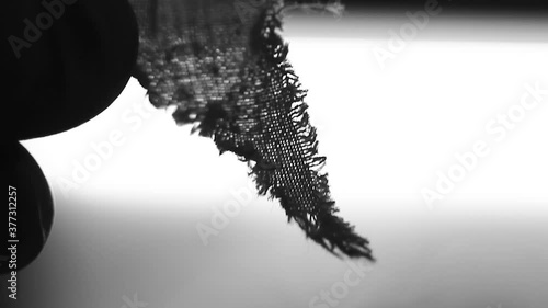 Small piece of cloth, held by fingered hands. Forensic. Analyze. Crime. Scene. 