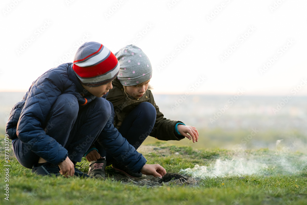Two children playing with fire outdoors in cold weather. Two children playing with fire outdoors in cold weather.