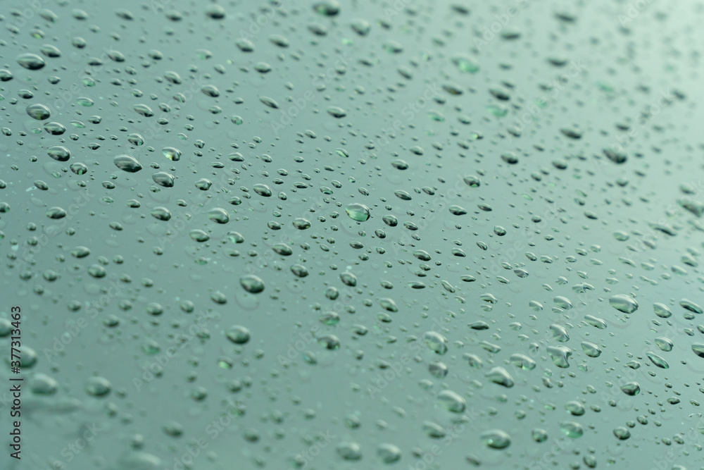 Raindrop on car window glass in morning rainy season for background or wallpaper. Drop of water on glass with blue sky and clouds. Raindrop on car window glass in morning rainy season for background or wallpaper. Drop of water on glass with blue sky and clouds.