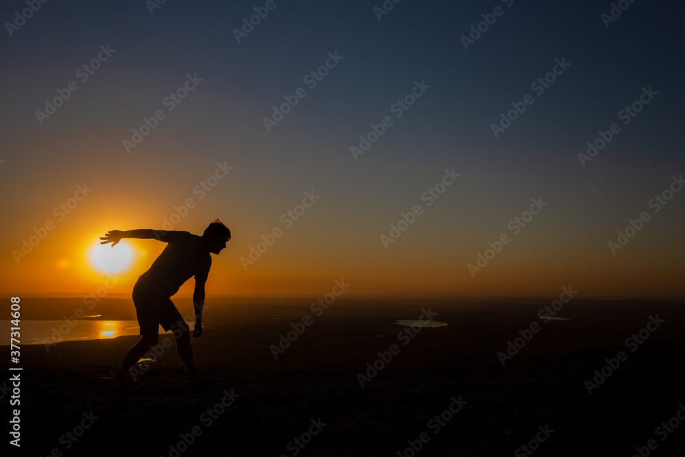 Fun, symbolic abstract photo at sunset-the sun-a ball with which a man depicts a sports competition - throwing a ball or a game of ball