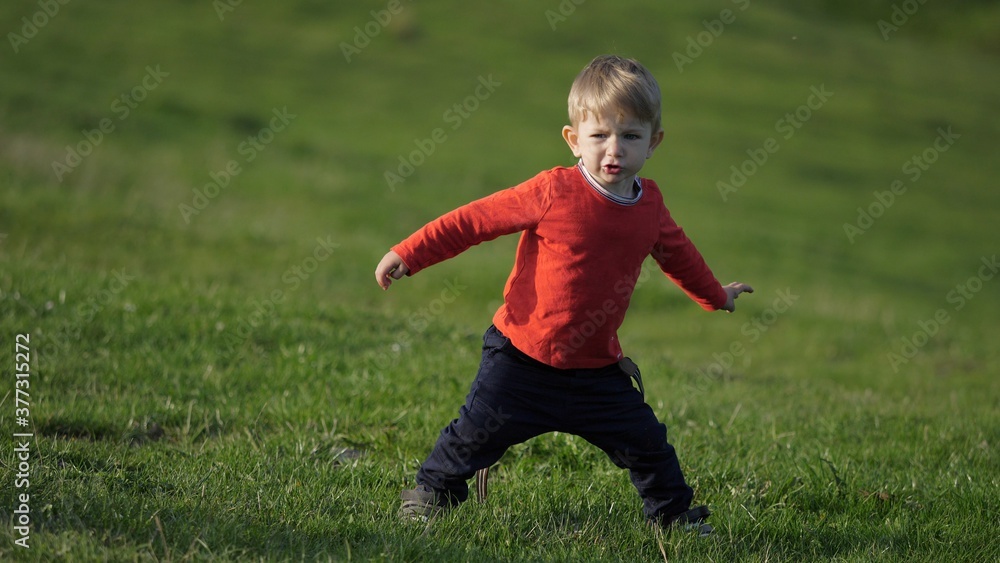 Funny blond hair child play on grass, play and sing Funny blond hair child play on grass, play and sing