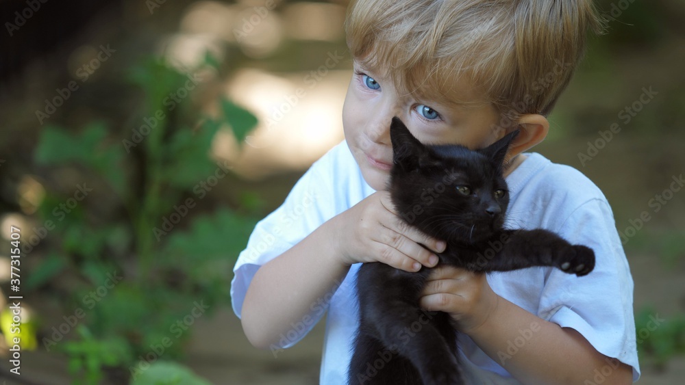 Portrait of blue eyes child lift up a black cat, face to face touching, pure animals love,