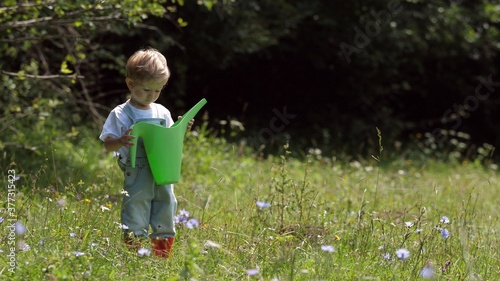 Funny little kid looking in the watering can