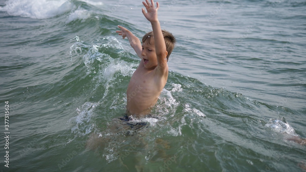 Boy play and jump in sea waves