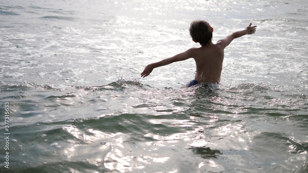 Fototapeta premium child with hands up goes into the sea