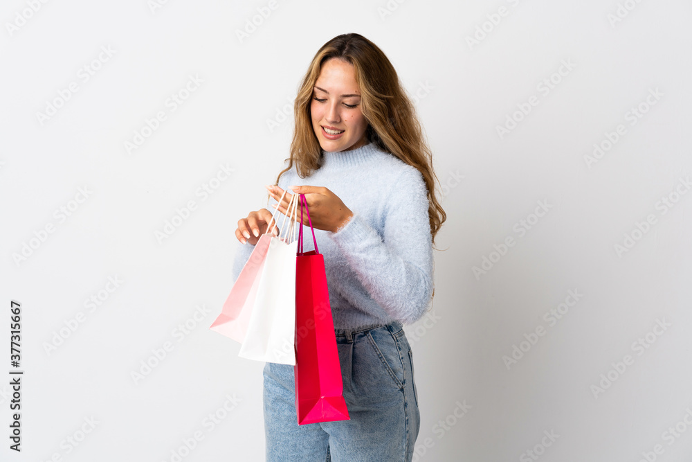 Young blonde woman isolated on white background holding shopping bags