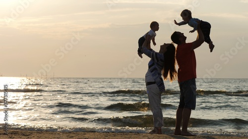 Photos Mother and father lifting up children at seaside, big brother waving hand to bab
