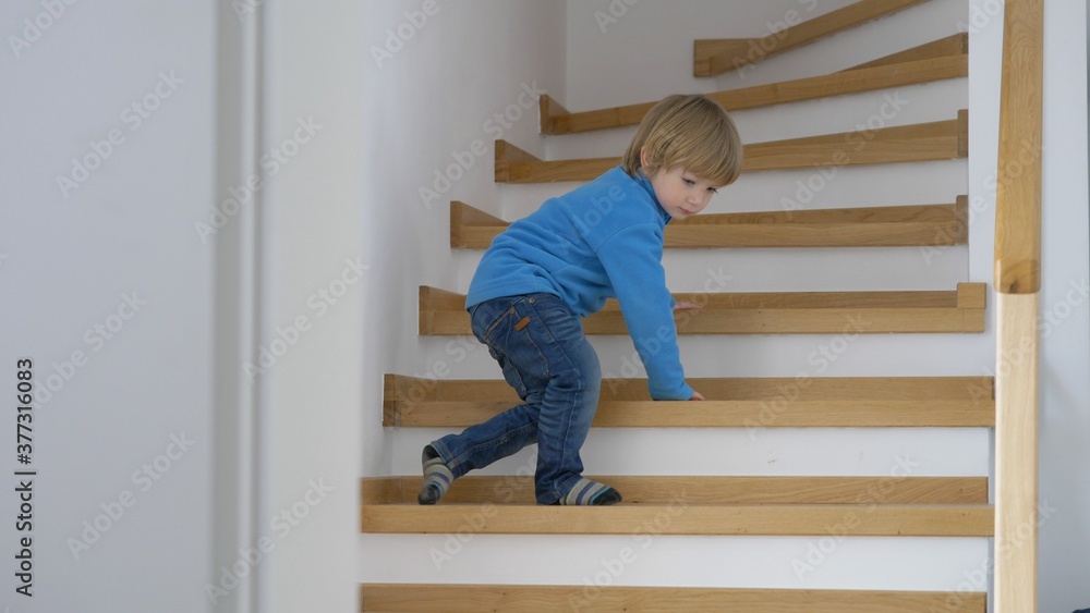 Blond hair child learn to go go down stairs, develop new skills home