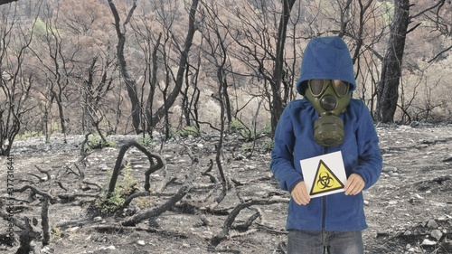 Child with gas mask with bio hazard label in polluted nature
