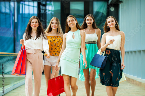 Five happy young women are walking in the mall