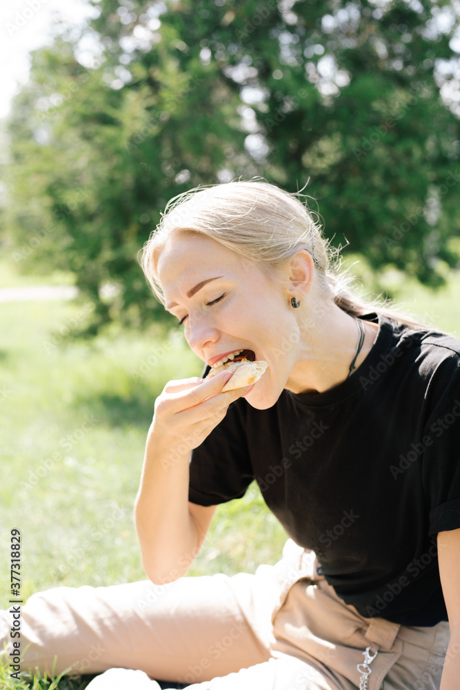 Beautiful girl eating trying tasting pizza outdoor in park Beautiful girl eating trying tasting pizza outdoor in park