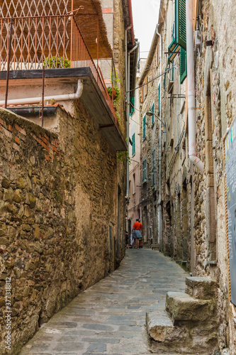 Fototapeta Naklejka Na Ścianę i Meble -  Lovely view of a quaint narrow road and houses with ancient facades on each side in the historic village Corniglia at the coastal area of Cinque Terre, Liguria, Italy.