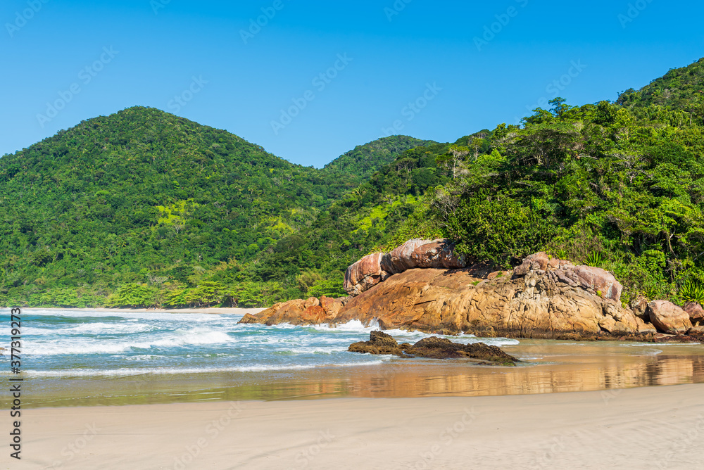 View of beach under mountains covered by tropical jungle in Brazil