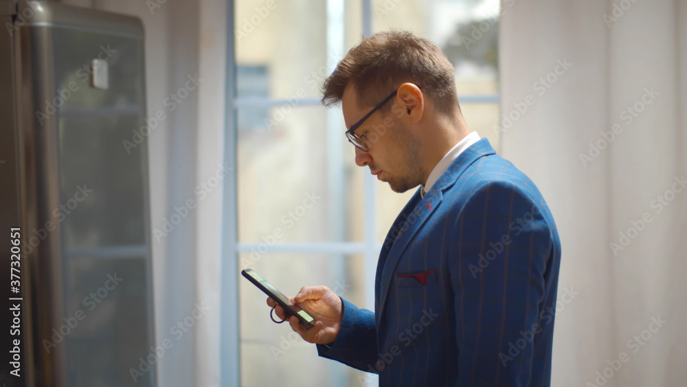 Handsome businessman using smartphone wearing suit and glasses and staying at home Handsome businessman using smartphone wearing suit and glasses and staying at home