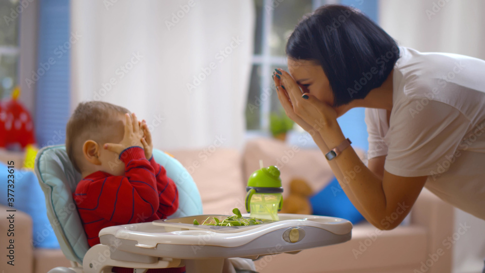 Mother and baby boy playing peekaboo and have fun at home. Stock Photo