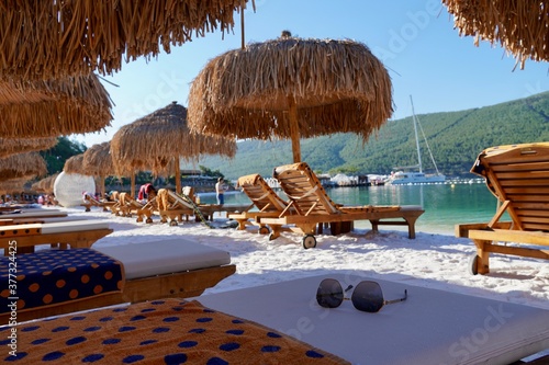 Bodrum, Turkey - August 2020: White sand and emerald water beach, bamboo palm trees, yachts and green hills on the horizon Concept Luxury tourism vacation relax relax