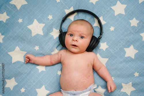 Obraz na płótnie Bebe escuchando musica con cascos inalambricos sobre la cama con estrellas w salonie