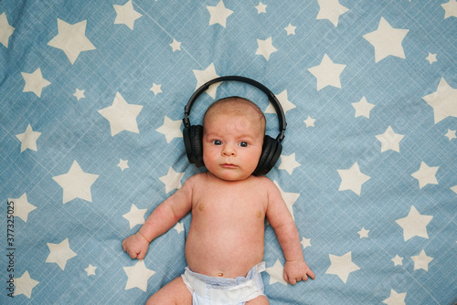 Obraz na płótnie Bebe escuchando musica con cascos inalambricos sobre la cama con estrellas w salonie